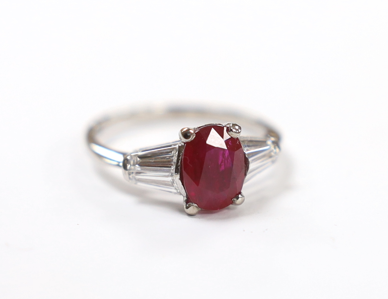 A white metal ruby ring with diamond set shoulders, housed in a Chow Tai Fook box gross weight 3.1grams